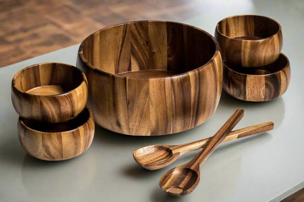 Kalmar Home 7-piece extra large acacia wood salad bowl set with two servers and four individual bowls on a wooden surface