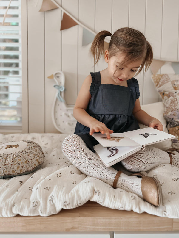 Young child wearing dark indigo organic cotton overall dress outdoors