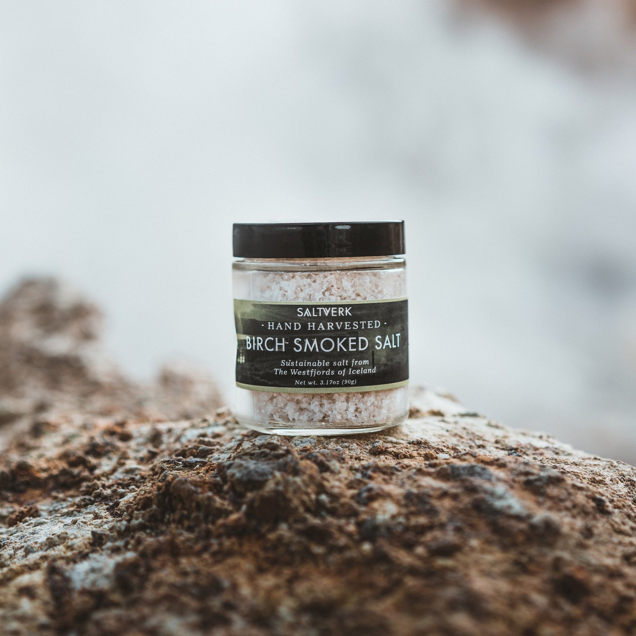 Jar of Saliverk Birch Smoked Salt on a rock with a blurred natural background