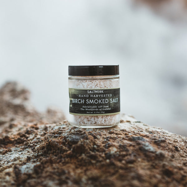 Jar of Saliverk Birch Smoked Salt on a rock with a blurred natural background