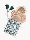 Set of woven coasters with a green and white patterned pouch on a white background