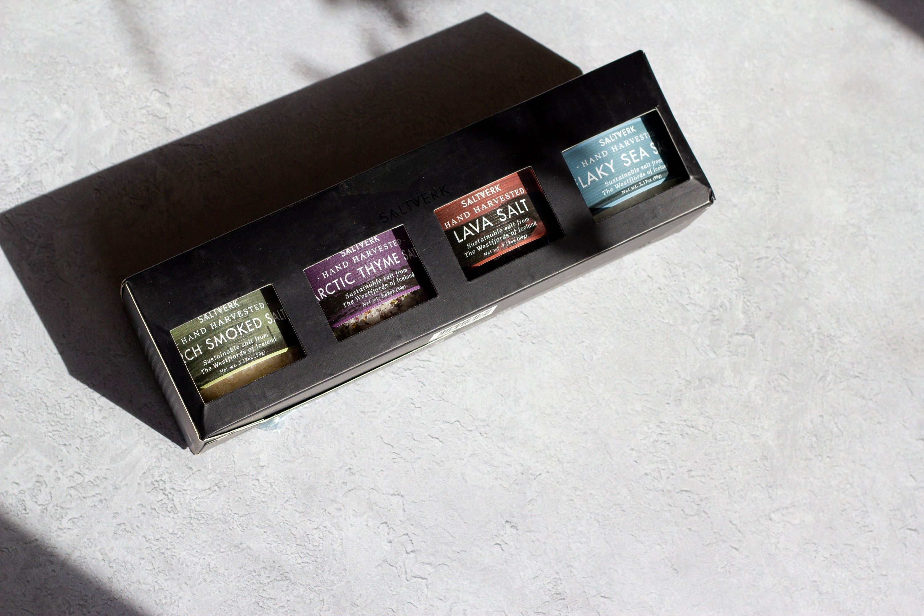 Set of four small containers with labels on a textured surface