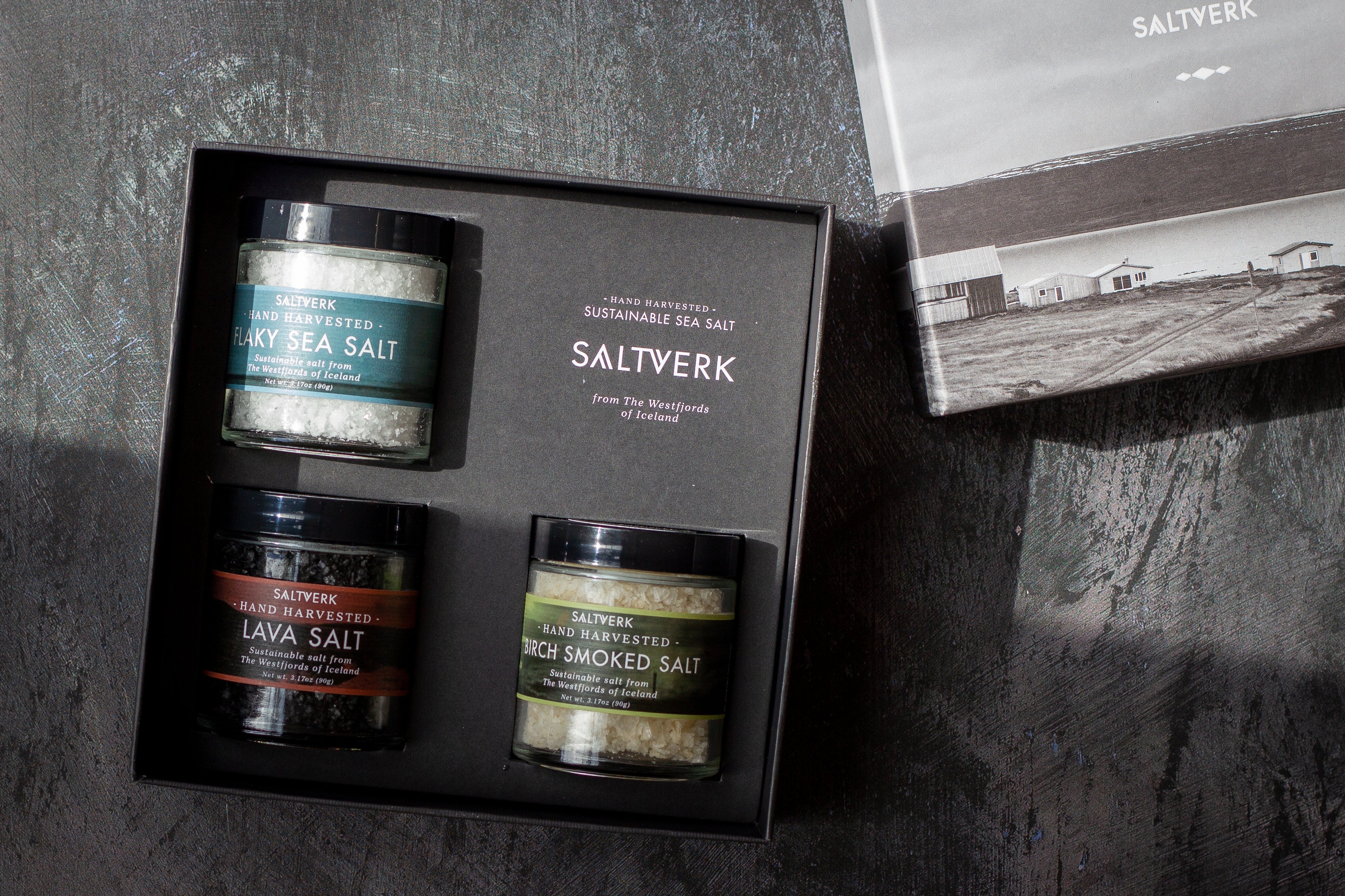Three salt containers in a box with 'Saltverk' branding on a dark surface.
