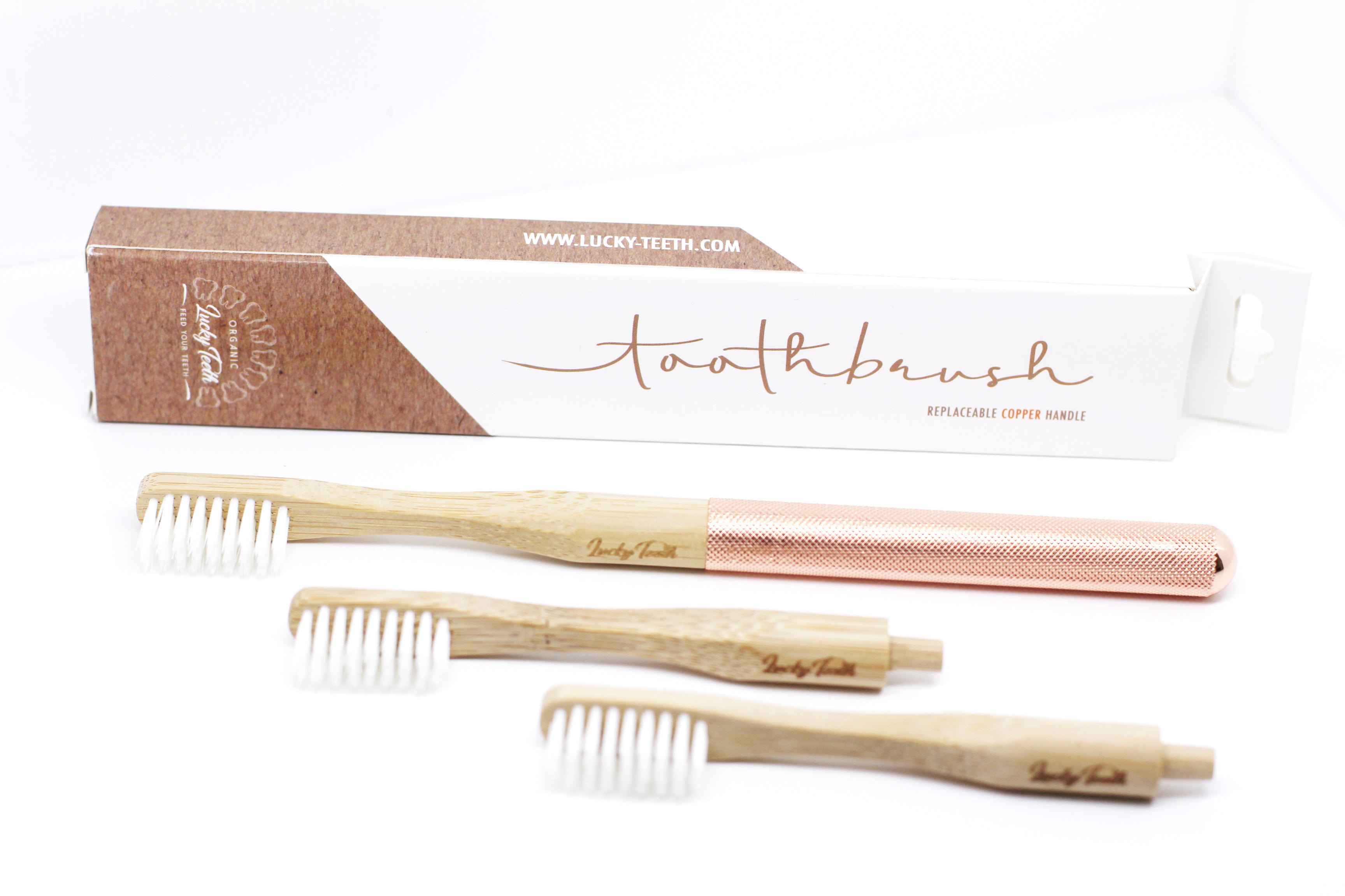 Set of three bamboo toothbrushes with a branded box on a white background