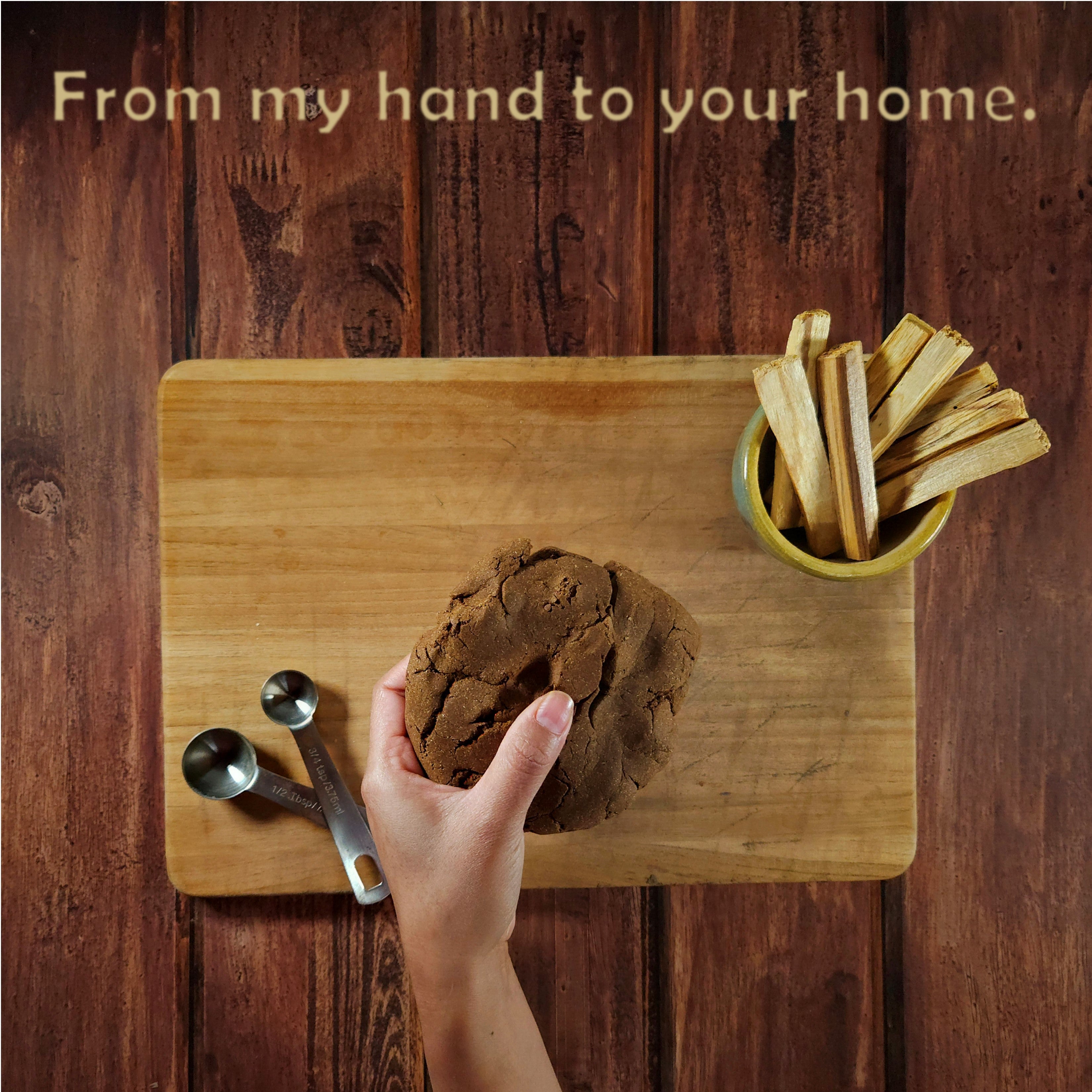 Hand holding a loaf of bread on a wooden cutting board with a rustic background.