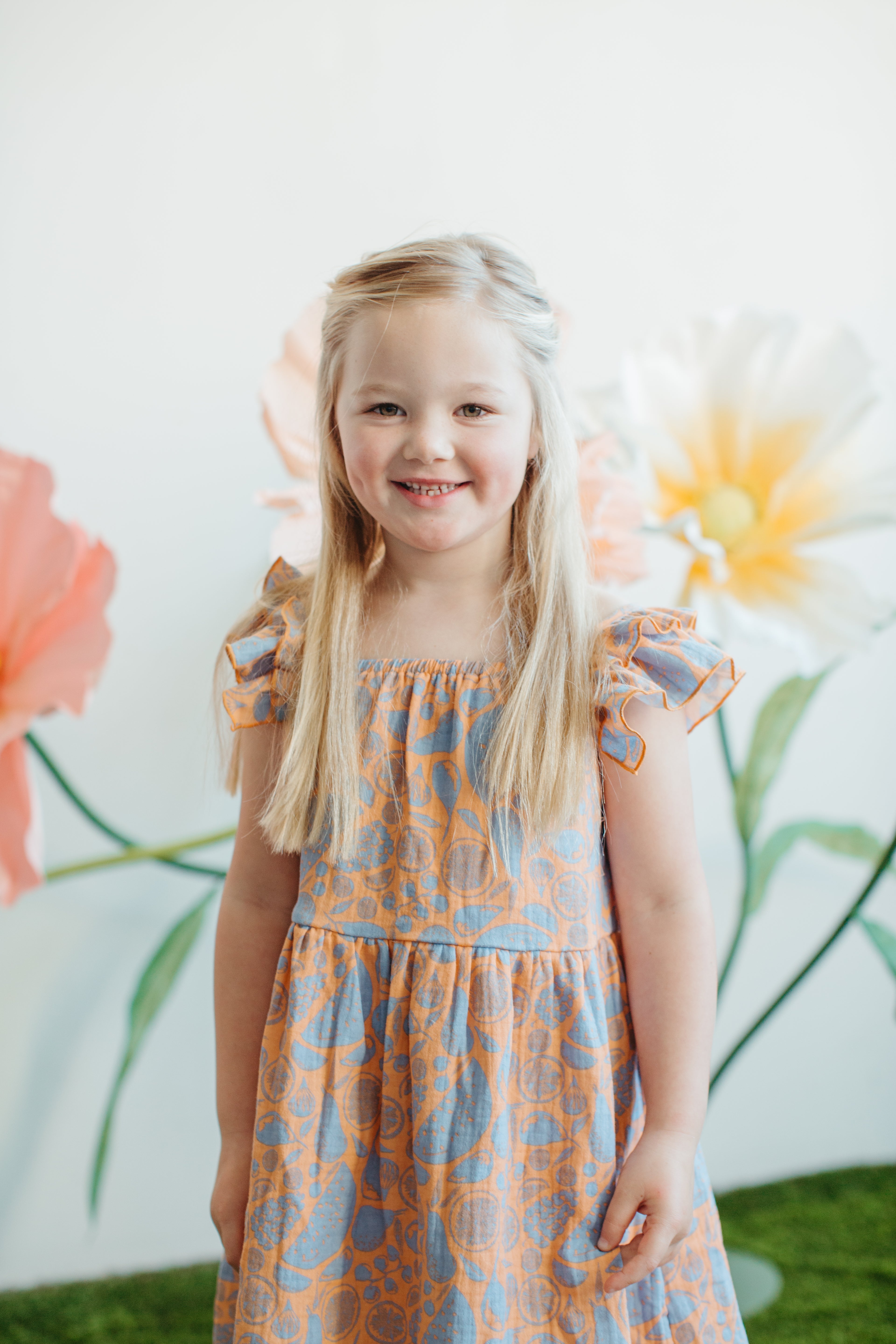 Close-up of Summer Bounty muslin dress showing flutter ruffle sleeves and elastic neckline on young child