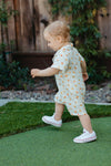 Close-up of Gingham Grove muslin romper showing green gingham print with playful citrus accents