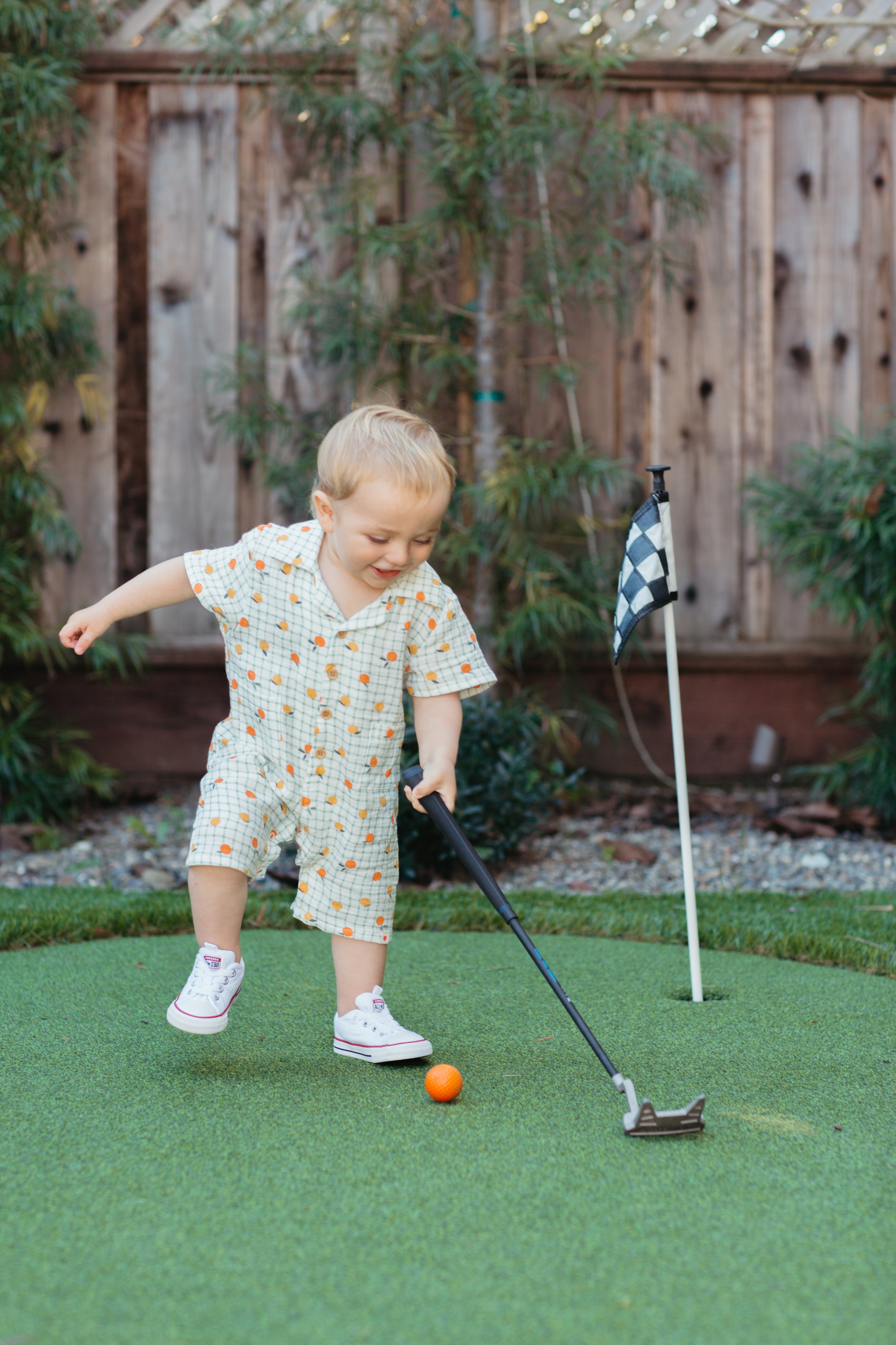 Baby wearing Apple Park Gingham Grove organic muslin romper with button front detail and cabana collar