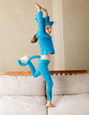 Child in a blue outfit with cat ears and tail standing on a couch