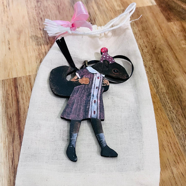 Small figurine of a person in a dress on a white cloth with a wooden surface underneath