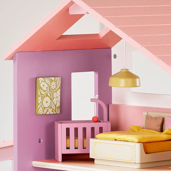 Pink dollhouse interior with a bed, crib, and lamp.