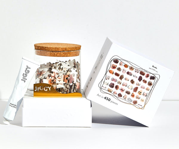 JIGGY Boobs puzzle pieces spread out on a flat surface with reusable glass jar packaging