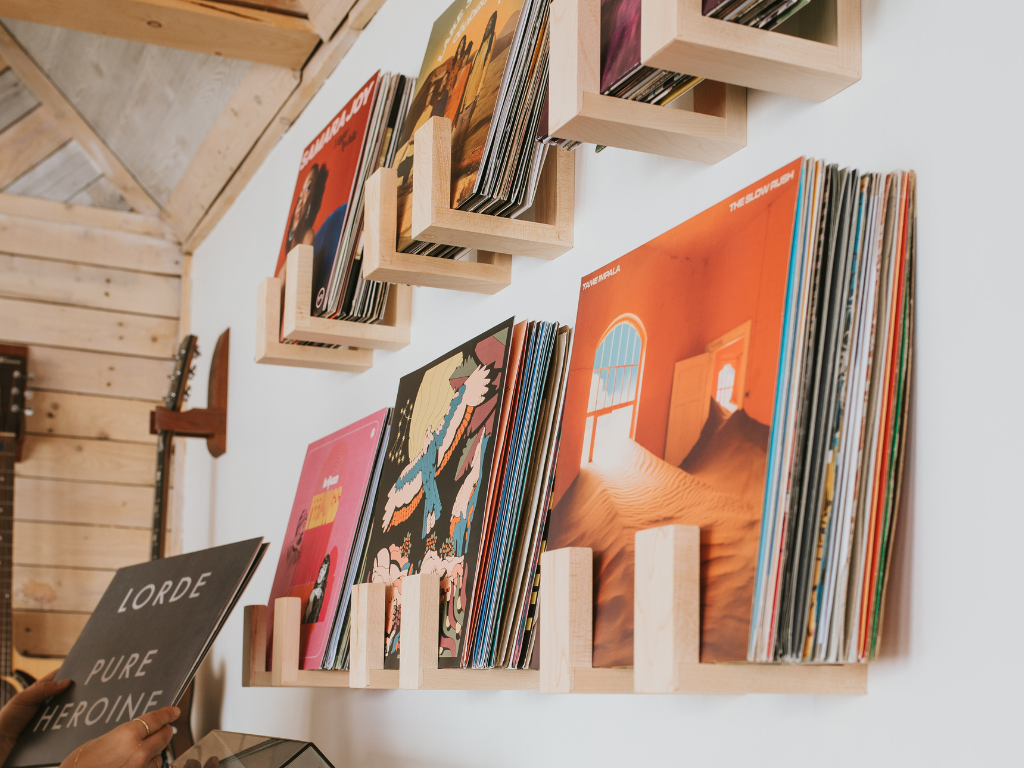 Vinyl records on wooden shelves against a white wall