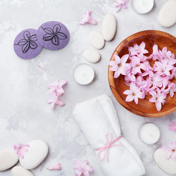 Spa setting with pink flowers, stones, and a towel on a light background