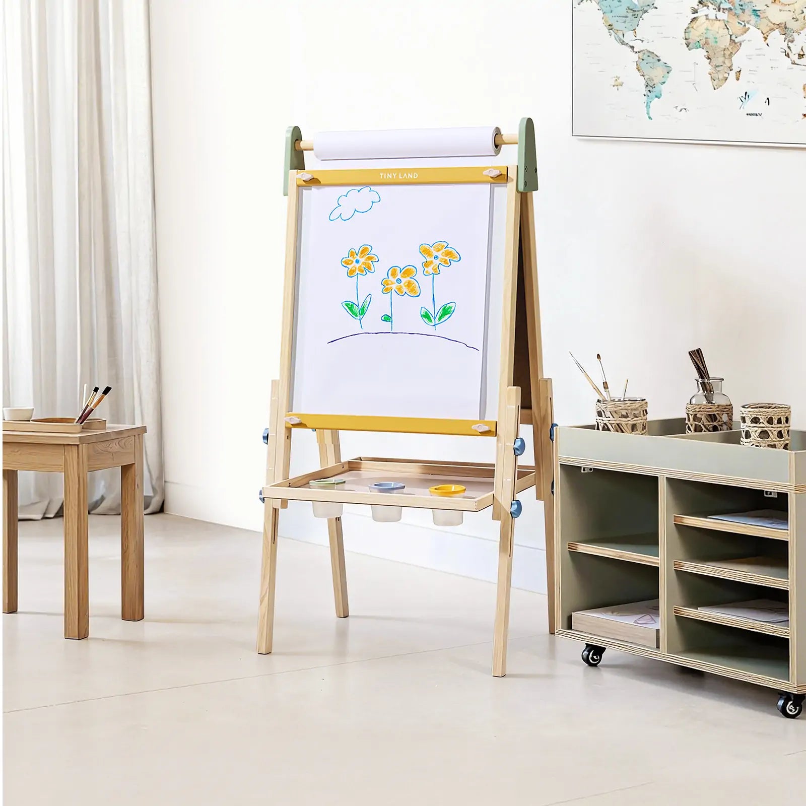 Wooden art easel with whiteboard and drawing area in a room with a world map and storage cart.