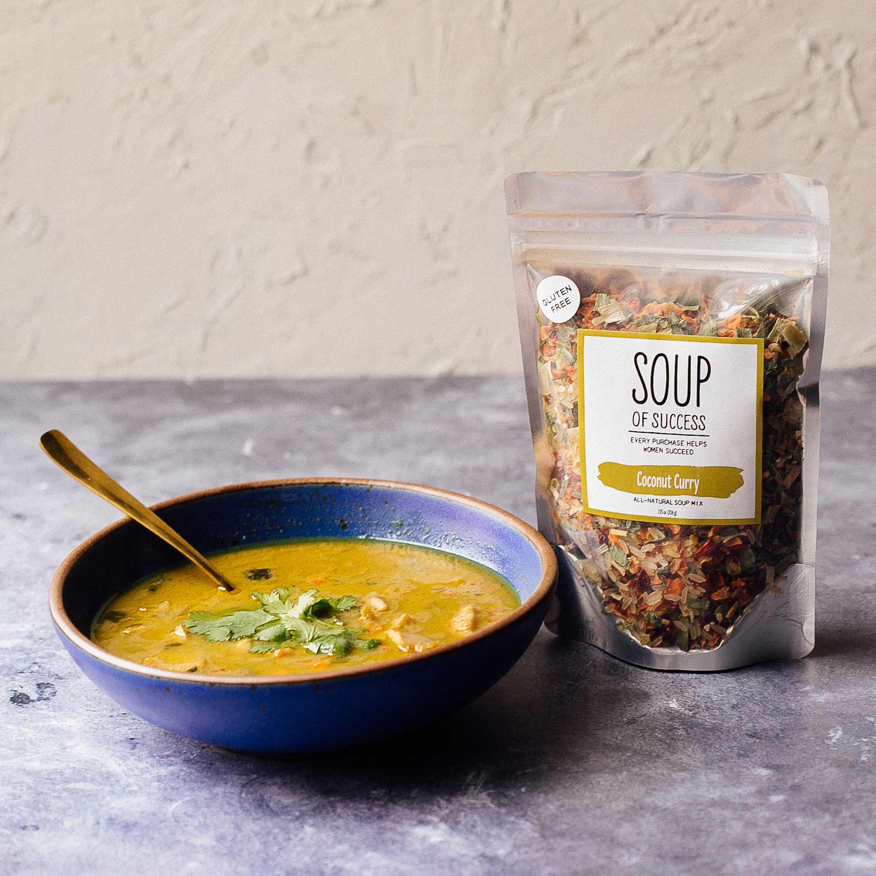 Bowl of soup with a package labeled 'Soup of Success' on a gray surface.