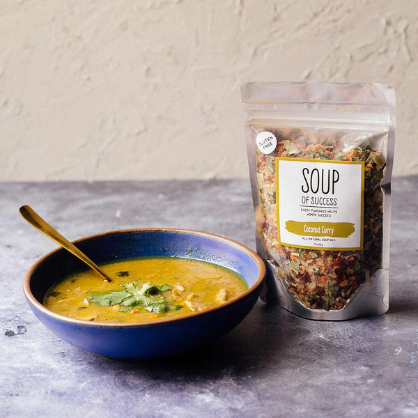 Bowl of soup with a package labeled 'Soup of Success' on a gray surface.
