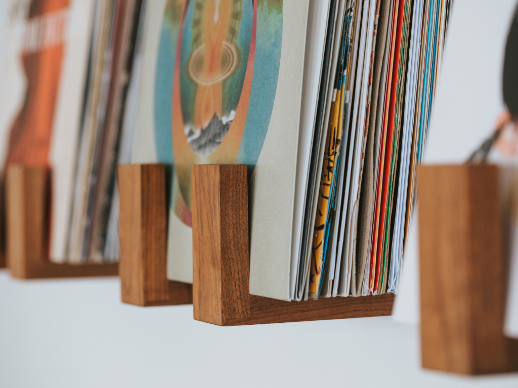 Collection of vinyl records on wooden stands against a white wall.