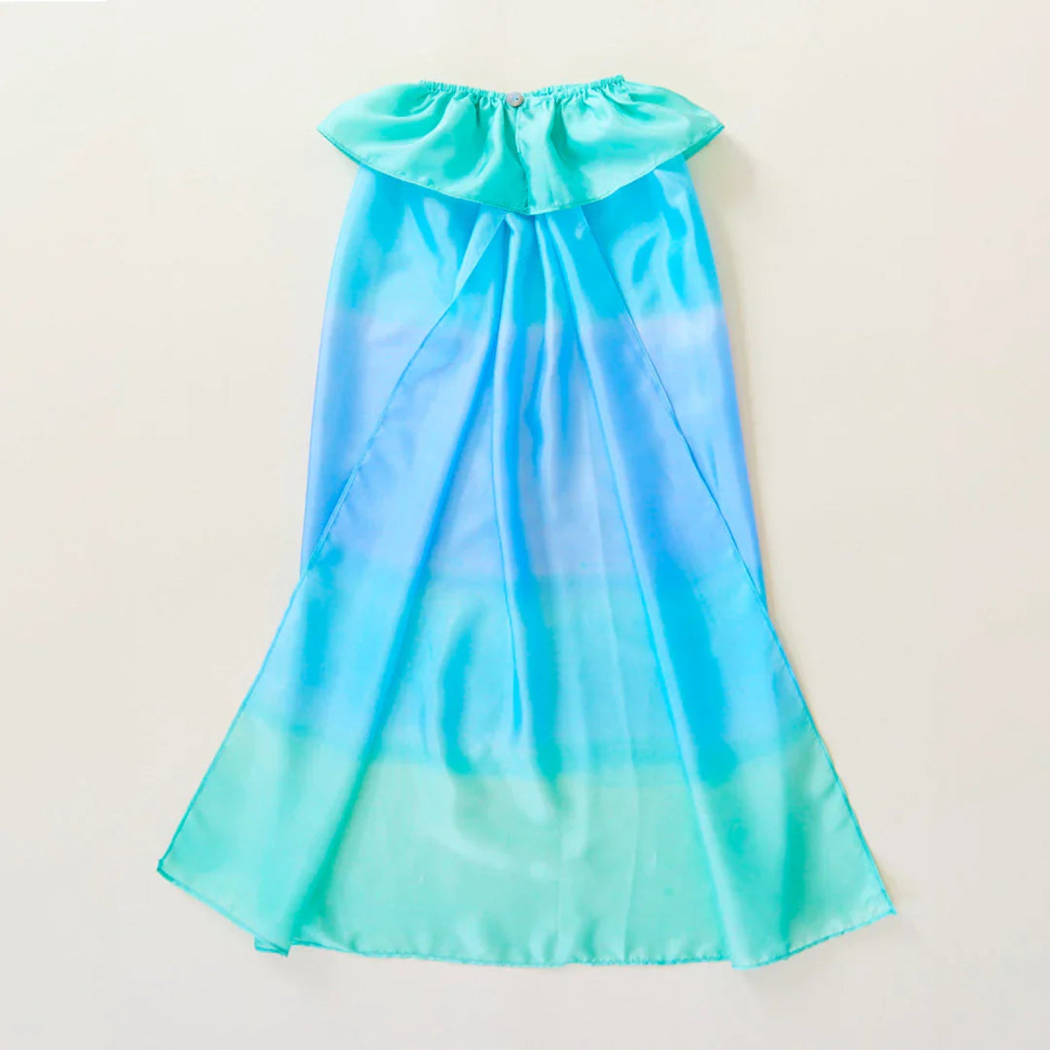 Gradient blue dress with ruffled neckline on a light beige background