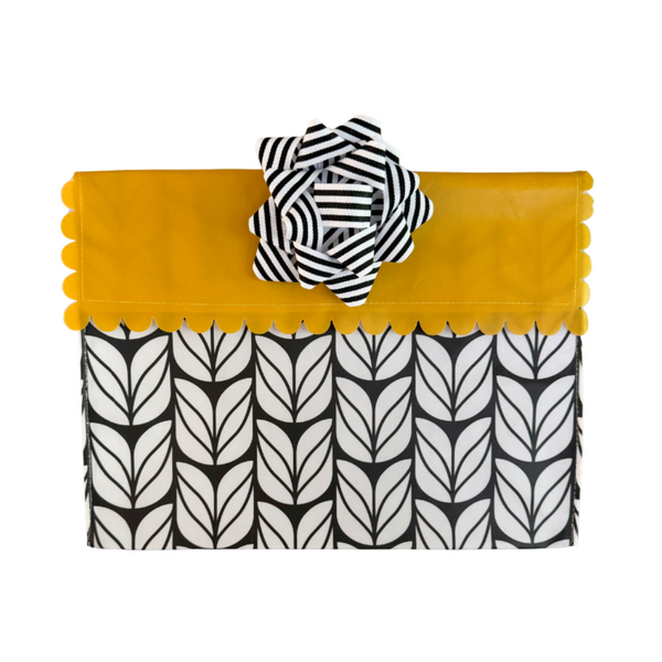 Yellow clutch with black and white patterned flap and flower accessory on a white background