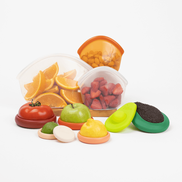 Set of toy fruits and vegetables with transparent containers holding oranges and strawberries on a white background.