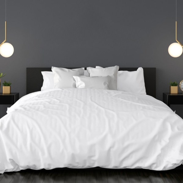 White bedding set on a bed with a dark headboard in a room with gray walls and pendant lights.