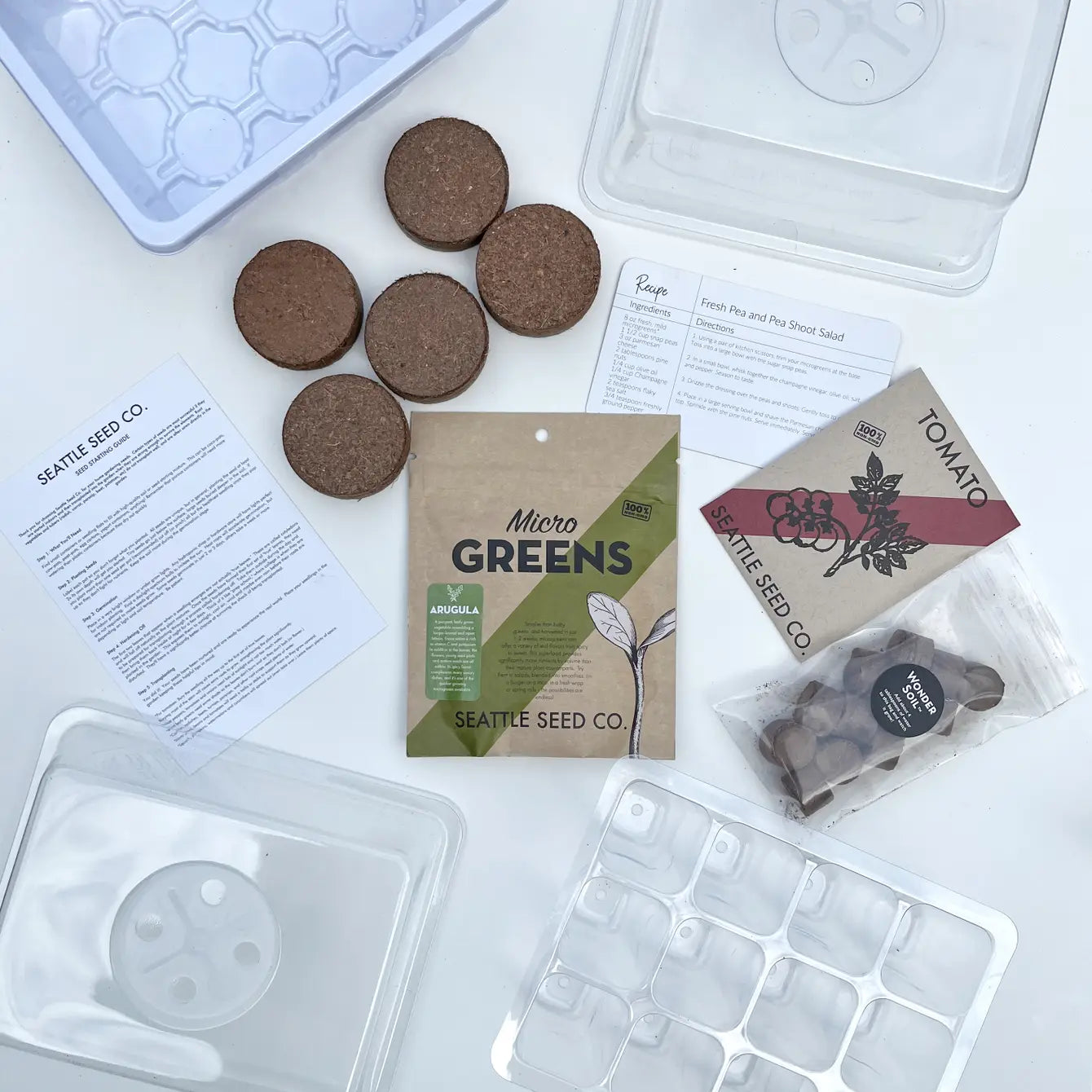 Seedling starter kit with seed packets, foam pots, and trays on a white background