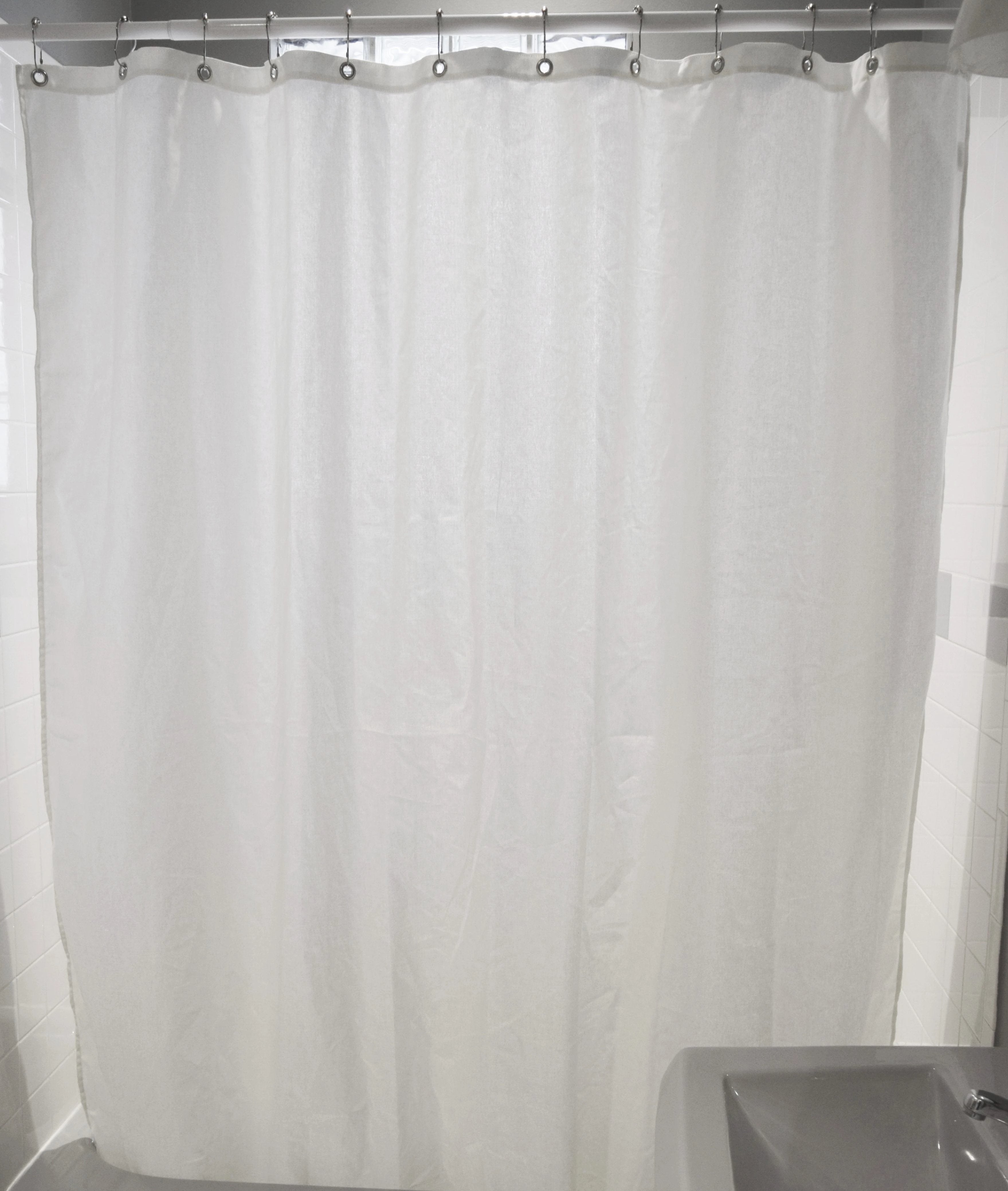 White shower curtain hanging in a bathroom with a sink visible.