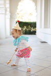 Child in clown costume with striped pants and party hat outdoors