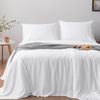 White bedspread with two pillows on a bed in a room setting.