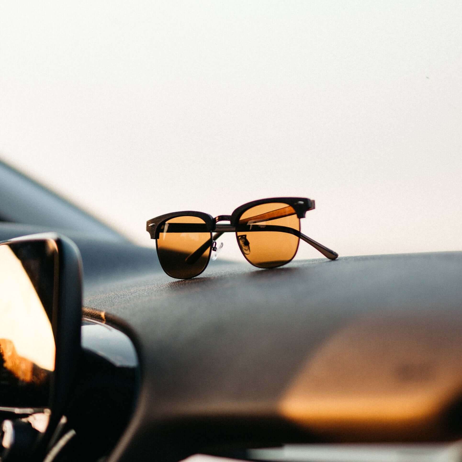 Sunglasses on a car dashboard with a blurred background