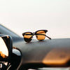 Sunglasses on a car dashboard with a blurred background