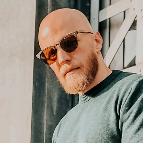 Man wearing sunglasses and a green sweater outdoors