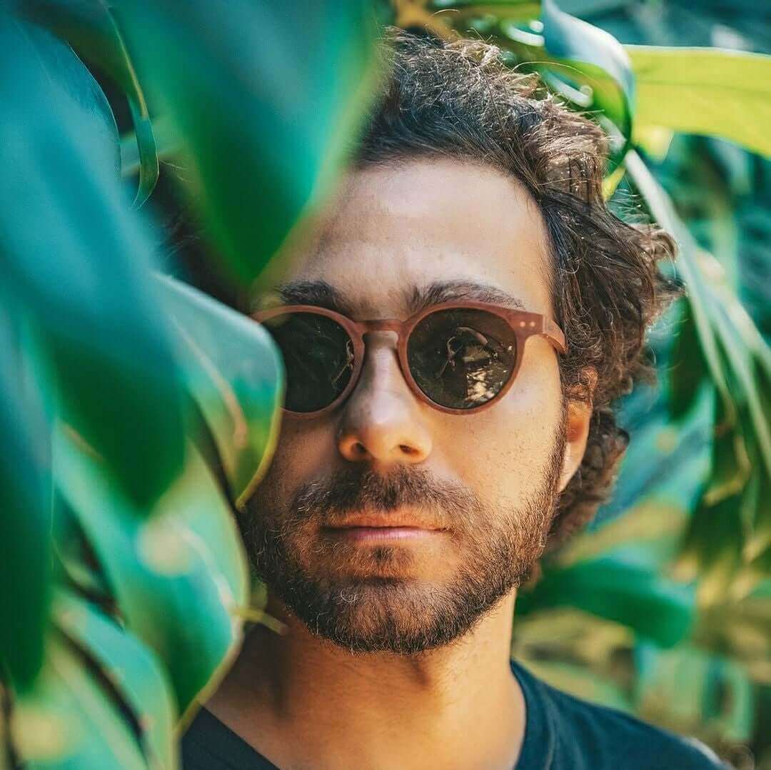Man wearing sunglasses among green leaves