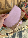 Hand holding a pink and brown wallet with a rustic background