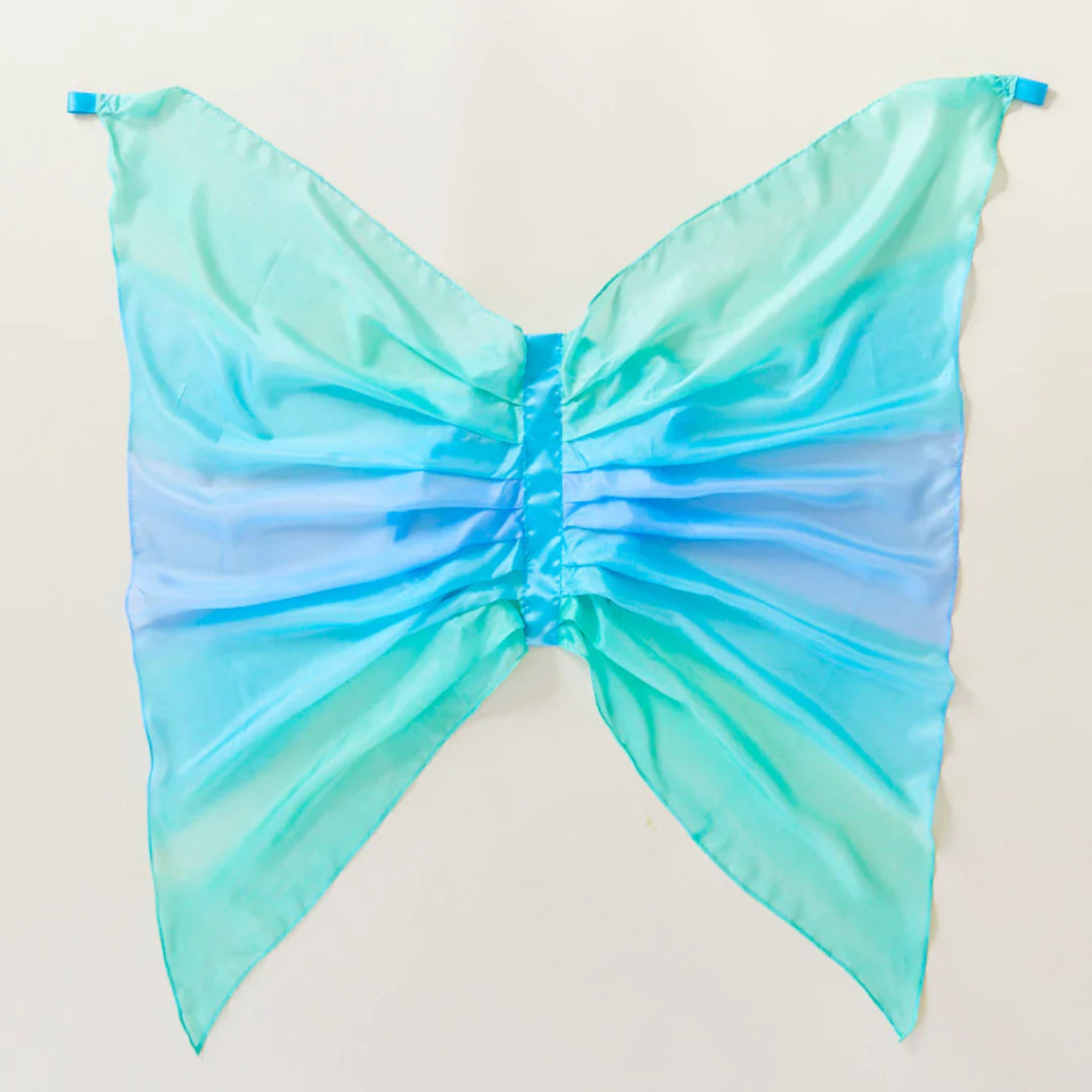 Gradient blue and green butterfly costume on a light beige background