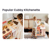 A children's play kitchen set shown in two lifestyle photos side by side under the heading 'Popular Cubby Kitchenette.' The left photo shows a young girl standing at the play kitchen counter with pretend food and utensils.