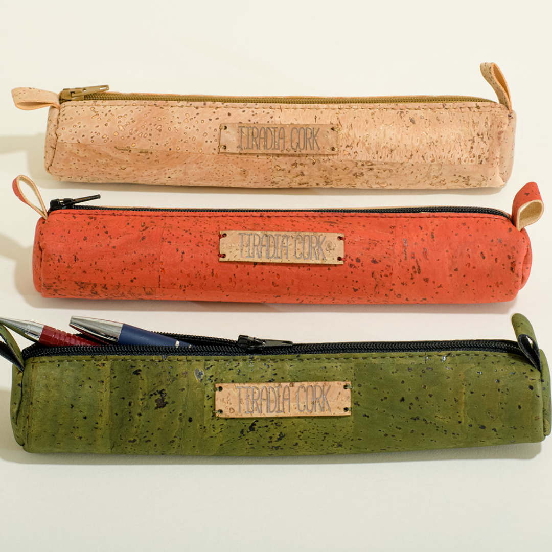 Three cork pencil cases in beige, orange, and green on a white background.