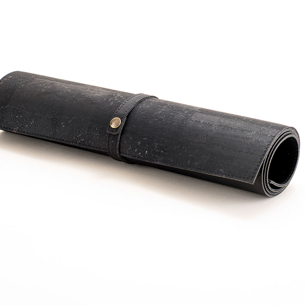 Black rolled-up mat with a strap and button on a white background