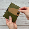 Green cork wallet with a card held by a hand on a wooden surface