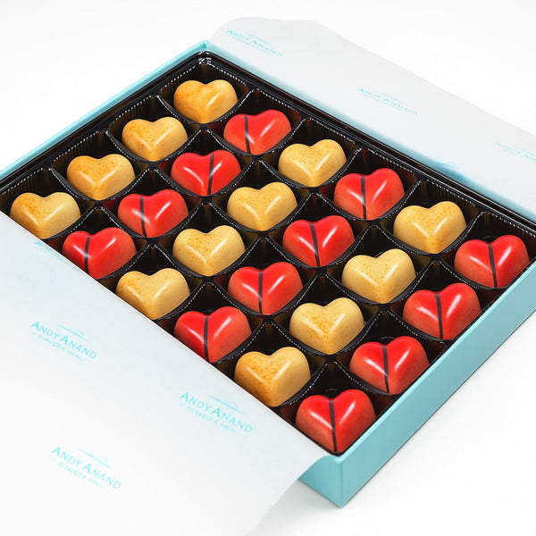 Box of heart-shaped chocolates in red and gold with a white background