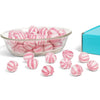 Pink and white striped candies in a glass bowl with scattered candies on a white background.