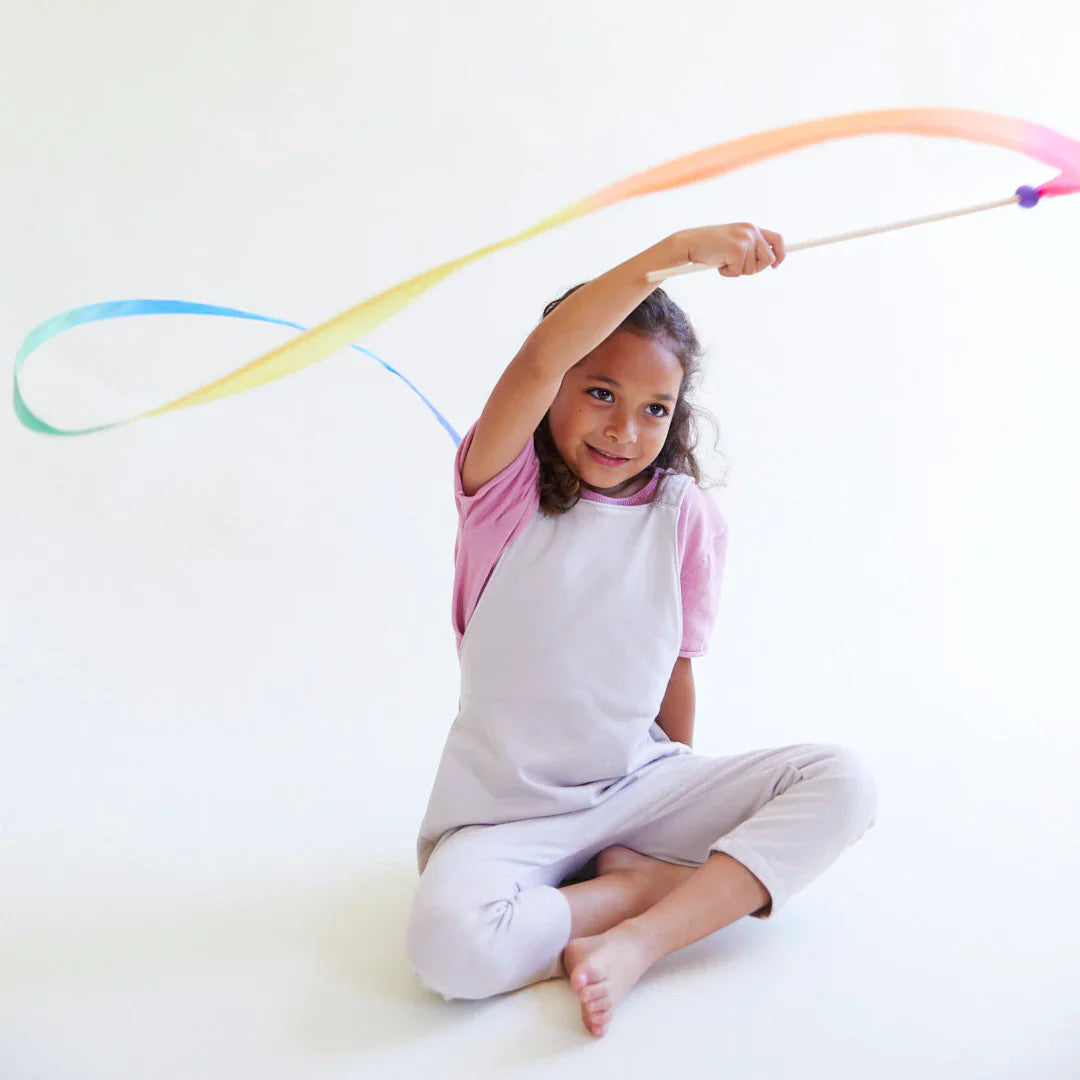 Child playing with a colorful ribbon on a white background