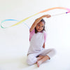 Child playing with a colorful ribbon on a white background