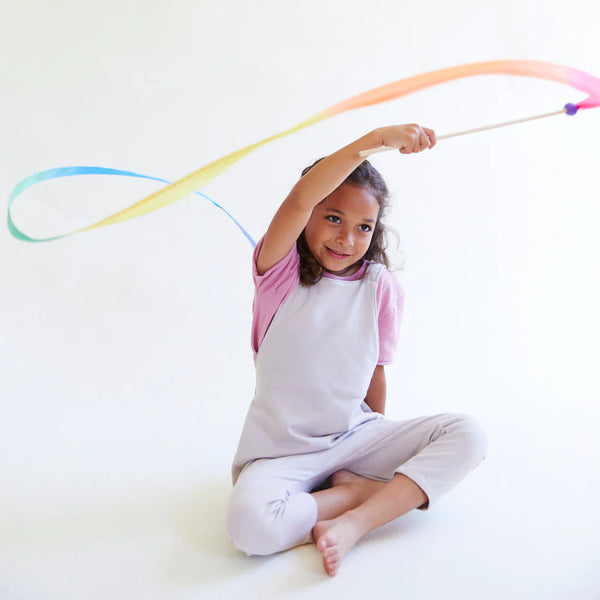 Child playing with a colorful ribbon on a white background