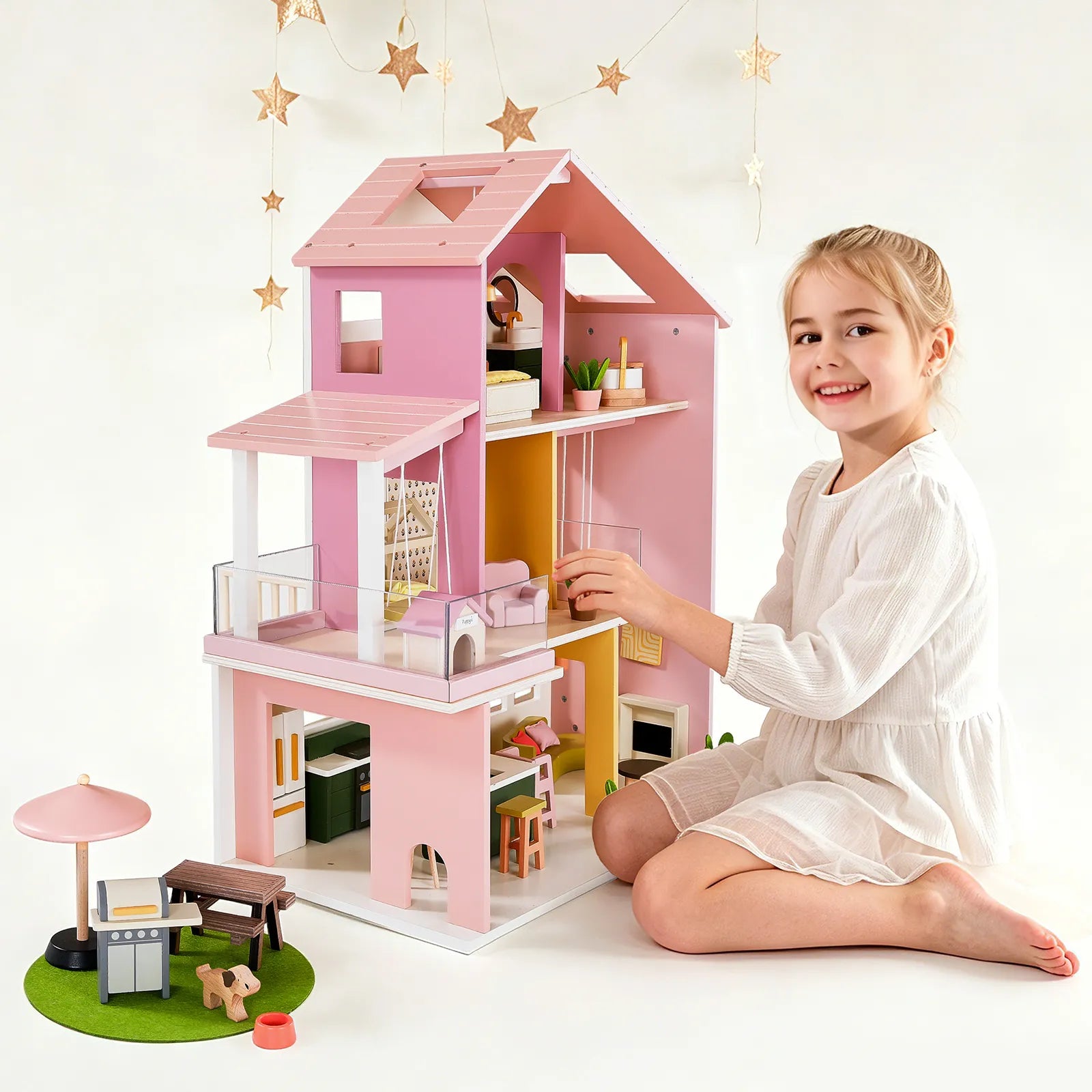 Young girl playing with a pink dollhouse on a white background