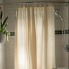 Beige shower curtain in a bathroom with a plant and tiled wall.