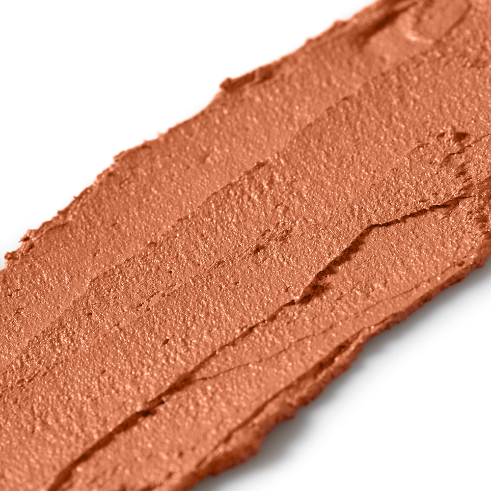 Close-up of a swatch of brown makeup cream on a white background