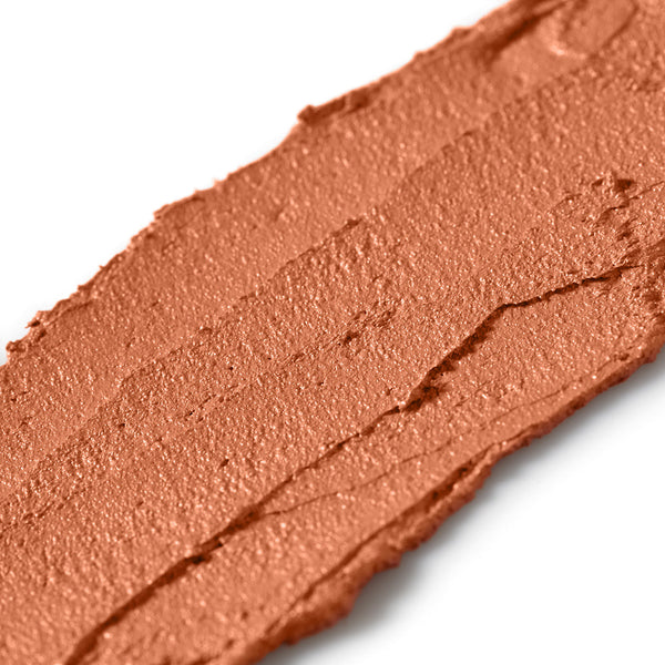 Close-up of a swatch of brown makeup cream on a white background