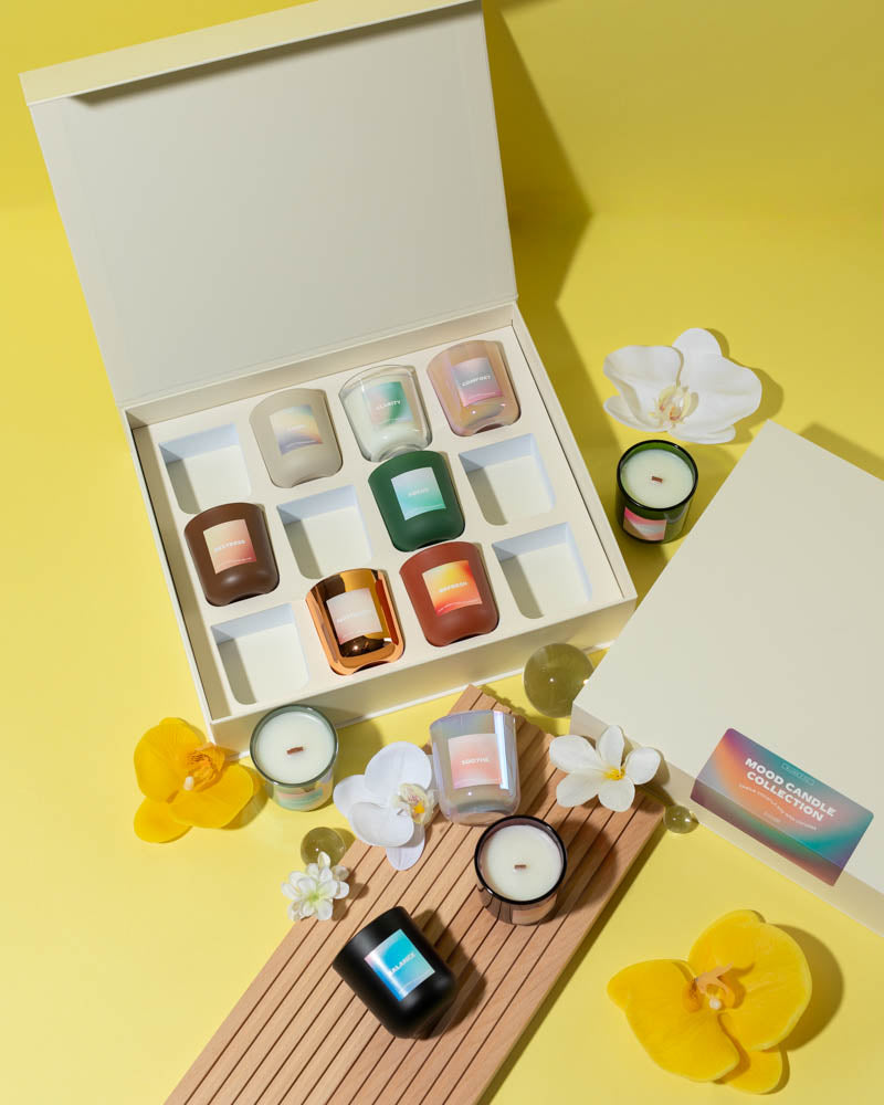 Collection of small candles in a box with decorative flowers on a yellow background